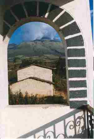 A mountain and house photographed through a stucco archway