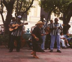 A band playing in a square while a woman dances