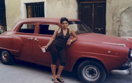 A woman leaning on a red car