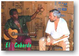 Two men, one with a guitar. Caption: El Cobarde